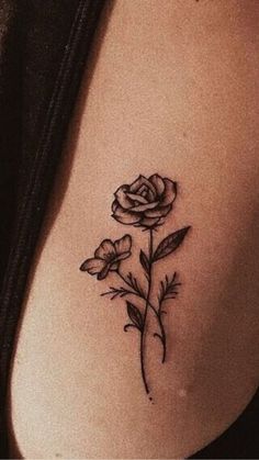 a rose tattoo on the back of a woman's left side ribcage