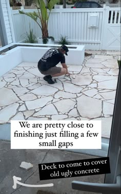 a man kneeling down on top of a cement floor next to a white wall and planter