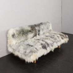 an animal print couch sitting on top of a black floor next to a white wall