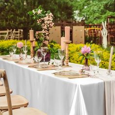 a long table set with place settings and flowers