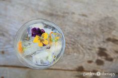 a glass filled with flowers sitting on top of a wooden table