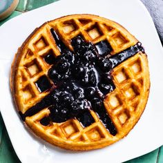 a waffle topped with blueberries and syrup on top of a white platter