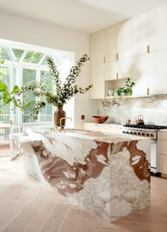 a kitchen with marble counter tops and white cabinets, along with an island in the middle