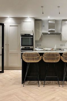 two wicker bar stools sit at the center of an island in this modern kitchen