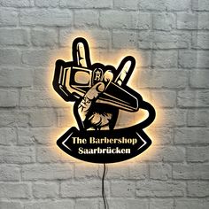 the barbershop sign is lit up against a white brick wall with a neon light