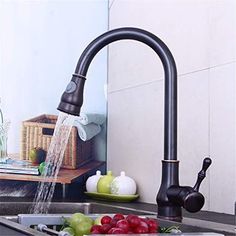 a faucet running water from a kitchen sink with fruit on the counter top