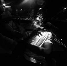 a man sitting in the passenger seat of a car at night with his headlight on