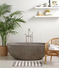 a bathtub sitting next to a chair and potted plant in a room with white walls