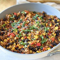 a large pot filled with mexican food and garnished with cilantro, black beans, corn