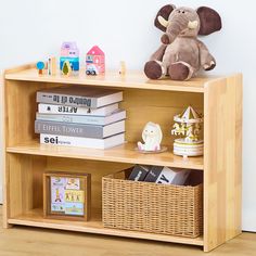 a wooden book shelf with books and stuffed animal on top, next to a white wall