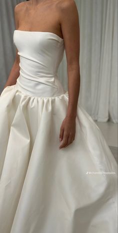 a woman in a white wedding dress with her hand on the back of her dress