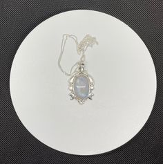 This enchanting pendant showcases a mesmerizing rainbow moonstone with an iridescent glow, set in a beautifully detailed sterling silver setting adorned with celestial stars and a crescent moon. Suspended on a 20" sterling silver chain, this piece captures the magic of the night sky, making it a perfect gift for dreamers and stargazers. This pendant is approximately 1 7/8" long and 1" wide. (not including the bail) Known for its soothing energy and ability to restore balance, the rainbow moonsto Celestial Silver Moonstone Necklace, Silver Celestial Moonstone Necklace, Silver Celestial Oval Jewelry, Celestial Silver Gemstone Necklace, Silver Moonstone Moon Necklaces, Celestial Silver Necklace With Gemstone, Magical Silver Moon Phase Jewelry, Silver Mystical Gemstone Necklace, Silver Gemstone Mystical Necklace