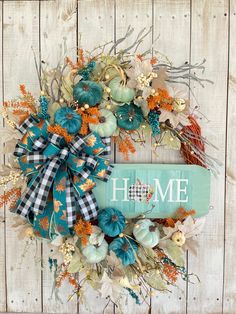 a wreath with the word home is hanging on a wooden wall next to pumpkins and gourds