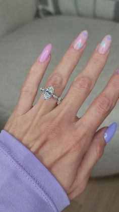 a woman's hand with pink and white manicured nails holding a diamond ring