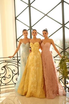 three beautiful women standing next to each other in formal dresses and posing for the camera