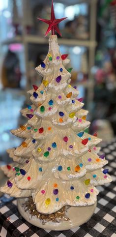 a white ceramic christmas tree sitting on top of a checkered tablecloth covered table