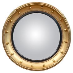 a round mirror with rivets on the edges and gold trimming around it