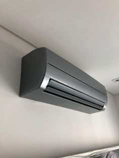 an air conditioner mounted on the wall above a bed in a room with white walls