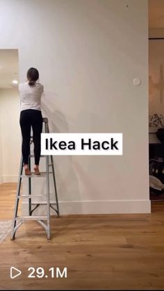 a woman standing on top of a ladder in front of a wall with the words ikea hack