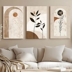 three paintings hang on the wall above a couch in a living room with white furniture