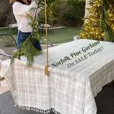 a table with a sign that says norfolk pine garlando on sale today in front of a christmas tree