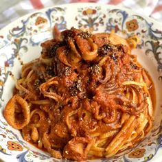 a plate full of pasta with sauce and onion rings