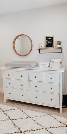 a white dresser and mirror in a room with a rug on the floor next to it