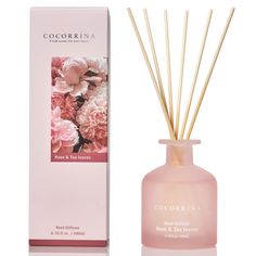 the reed sticks are next to a pink bottle with flowers on it and an empty box