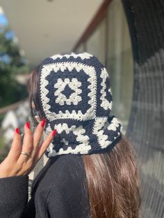 a woman with red nails wearing a crocheted hat