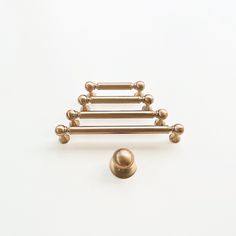 a gold pin with balls on it sitting next to a white wall and a ball