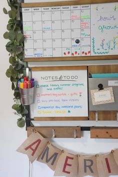 a bulletin board with writing on it next to an american flag and potted plant