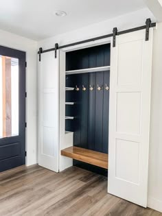 an empty room with two open doors and a bench in front of the closet door