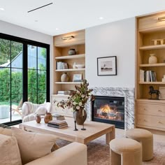 a living room filled with furniture and a fire place in front of a large window