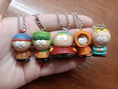 a person holding five cartoon key chains in their hand