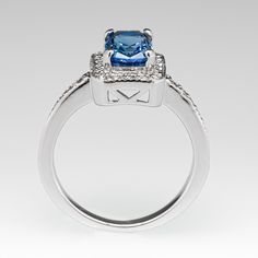 This gorgeous no heat blue sapphire ring is centered with a 1.64 carat cushion cut sapphire set into a four-prong head and is bordered with eighteen (18), bead set, round brilliant cut diamonds. The top face of the shank is accented with a row of seven (7), bead set, round brilliant cut diamonds on each side. The ring measures 10.2mm at the top, rises 6.4mm above the finger, tapering to 1.7mm wide and 1.1mm thick at the base of the shank. The ring is currently a size 4.75 and we offer complimentary resizing to fit. Formal Sapphire Ring With Radiant Cut And Halo Setting, Classic Blue Radiant Cut Sapphire Ring, Formal Sapphire Ring With Radiant Halo Setting, Formal Radiant Cut Sapphire Ring With Halo Setting, Blue Cushion Cut Diamond Promise Ring, Blue Sapphire Ring In Radiant Cut Platinum, Blue Sapphire Ring With Asscher Cut And Accent Stones, Blue Sapphire Ring With Radiant Cut And Accent Stones, Cushion Cut Sapphire Ring With Halo Setting