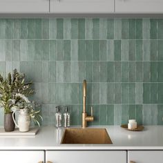 a kitchen with green tiles on the backsplash and gold faucet handles