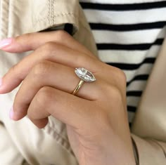 a woman's hand wearing a gold ring with a pear shaped diamond on it