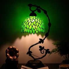 a green lamp sitting on top of a table next to a book and coffee cup