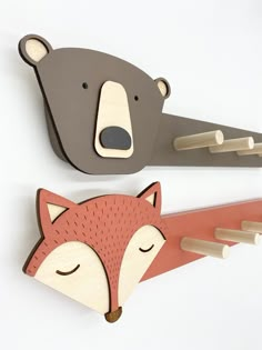 two wooden wall hooks with faces of animals, one bear and the other fox on them