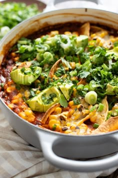 a casserole dish with tortilla chips and avocado garnish