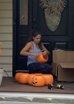 a woman sitting on the front steps with pumpkins in front of her and an orange jack - o'- lantern