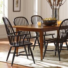 a dining room table with four chairs and a bowl of fruit on top of it