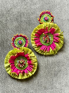 two pairs of colorful earrings sitting on top of a gray surface next to each other