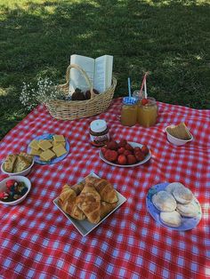 a picnic table set up with bread, fruit and jams on it in the grass