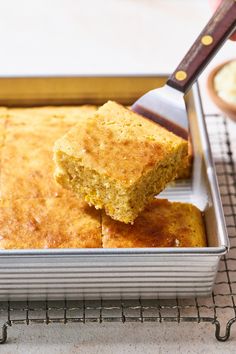 someone is cutting into a cornbread in a pan