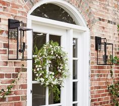 a wreath is hanging on the front door of a brick building with white trimming