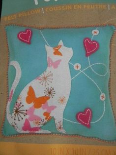 a white cat sitting on top of a blue pillow with butterflies and hearts around it