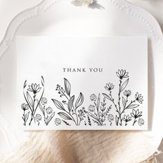 a thank you card with black and white flowers on it, sitting on a plate