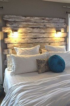 a bed with white sheets, pillows and wooden headboard made from pallet boards