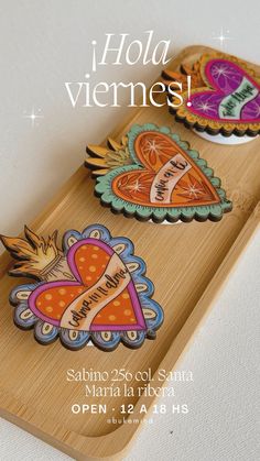 a wooden tray with two heart shaped magnets on it and the words hola vermes written in spanish